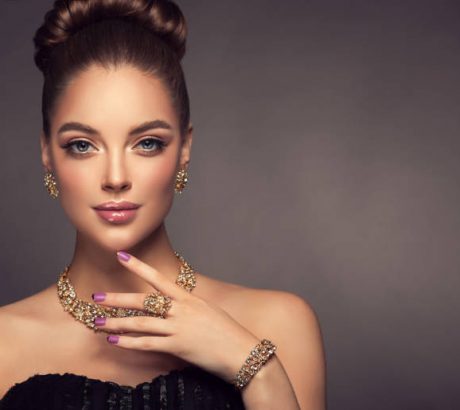 Beauty portrait of young gorgeous woman is dressed in a jewelry set of necklace, ring and earings. Pretty  blue eyed model is demonstrating an attractive make up and manicure.